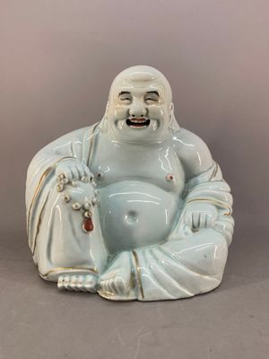a statue of a laughing buddha sitting on the ground