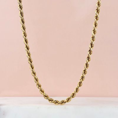 un collier à maillons dorés sur fond rose