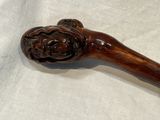 a wooden stick with a carved lion head on it