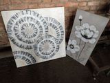 two paintings of black and white flowers on a brick wall