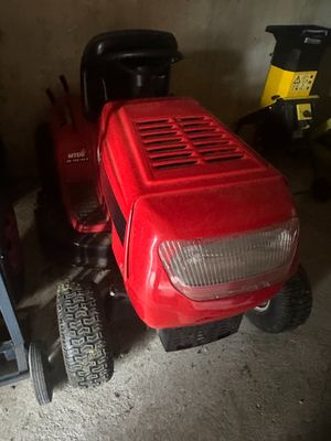 une tondeuse à gazon rouge rangée dans un garage à côté d'autres tondeuses à gazon