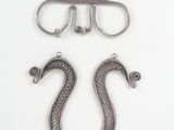 two pairs of metal hooks and a pair of scissors on a white surface