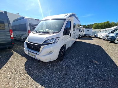 un camping-car blanc garé sur un parking à côté d'autres véhicules