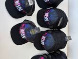 six black baseball caps hanging on a white wall in a room