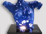 a blue sculpture on a black stand with a light on it