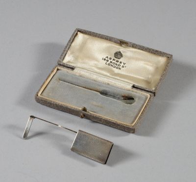 une pince à cravate ancienne en métal argenté, présentée dans un coffret contenant une petite pince à cravate