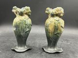 une paire de vases en céramique verts ornés d'oiseaux, posés sur une table