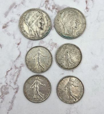six types différents de pièces d'argent posées sur une surface en marbre