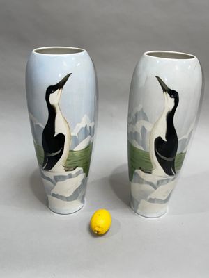 two vases with birds painted on them sitting next to a yellow ball
