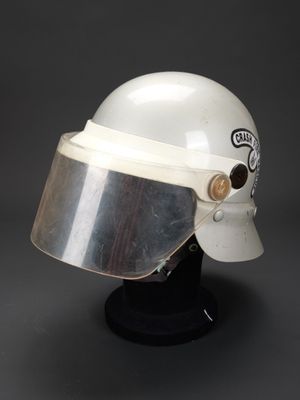 un vieux casque muni d'une visière métallique, posé sur un socle noir