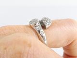 a person holding a silver ring with two hearts on it