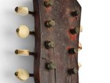 a close up of an old guitar head with strings