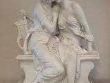 une statue représentant une femme et un homme assis sur un banc