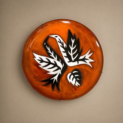 une assiette en céramique décorée d'un oiseau, accrochée au mur