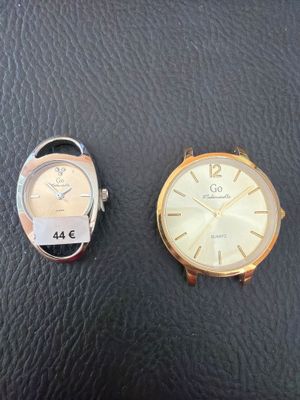 two watches sitting next to each other on a black surface