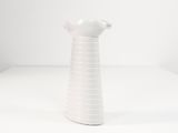 a white vase sitting on a table with a white background