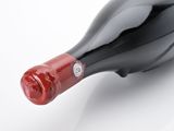a bottle of red wine on a white surface
