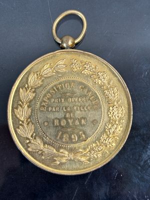 une vieille médaille en or entourée d'une couronne, posée sur un fond noir