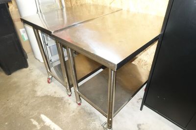 une table en acier inoxydable avec deux étagères et un meuble noir