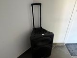 a black piece of luggage sitting against a white wall