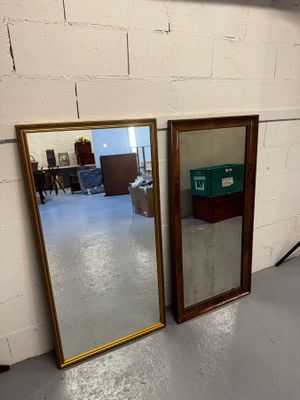 Deux miroirs sont posés par terre devant un mur de briques blanches.