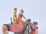 two figurines of a man and a woman riding in a motorcycle