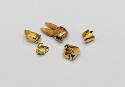 three pieces of gold plated metal on a white surface