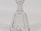 a clear glass bottle with a stopper on a white surface