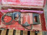 une caisse rouge contenant une perceuse, posée sur une palette