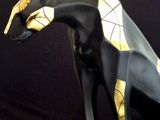 statue of a black and gold cat sitting on a black base