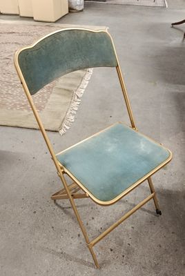 une chaise pliante bleue et dorée posée dans une pièce