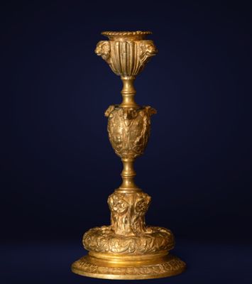 an antique gold vase on a stand against a dark blue background