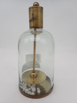 une petite bouteille en verre avec un socle en bois et une poignée dorée