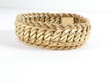 a close up of a gold bracelet on a white surface