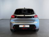 the rear end of a silver car in a room with a white wall