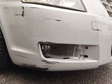 a close up of a white car with a dent in the front