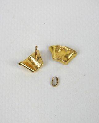 une paire de boucles d'oreilles en or sur une surface blanche