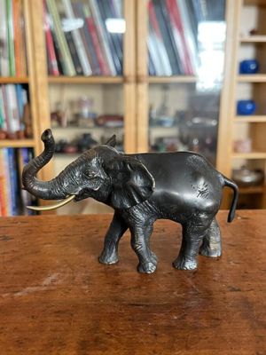 statue d'un éléphant posée sur une table devant une bibliothèque