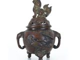 un vase en bronze surmonté de deux oiseaux