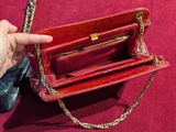 a person holding a red purse on a red surface