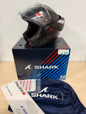 Le casque en forme de requin est posé sur une boîte posée sur la table.