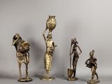 trois figurines en bronze représentant des femmes et un homme portant un pot sur la tête