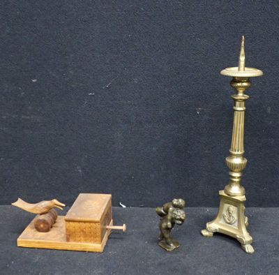 une petite statue représentant un homme debout à côté d'une bougie et d'une boîte