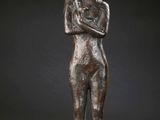 une statue en bronze représentant une femme debout, les bras croisés