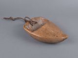 an old wooden shoe with a string attached to it on a gray surface
