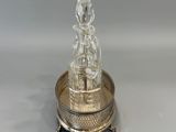 a silver plate with a glass figurine on top of it