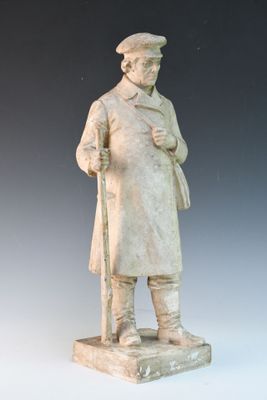statue d'un homme portant un chapeau et un manteau, tenant une canne