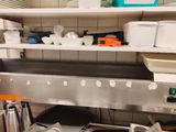 un grand évier en métal dans une cuisine où les étagères sont remplies de vaisselle