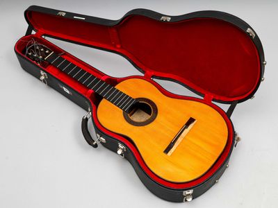 une guitare dans un étui, posée sur une surface blanche