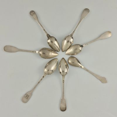 six cuillères en argent disposées en cercle sur une surface blanche